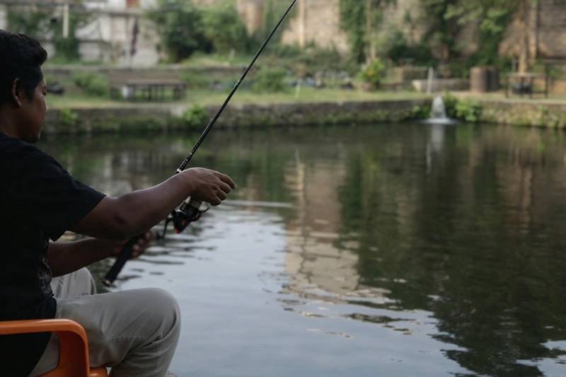 Seorang pengunjung sedang asik memainkan kail menunggu ikan menyambar di Pondok Mancing Cukanggalih | Foto: Dok. Widi Hatmoko